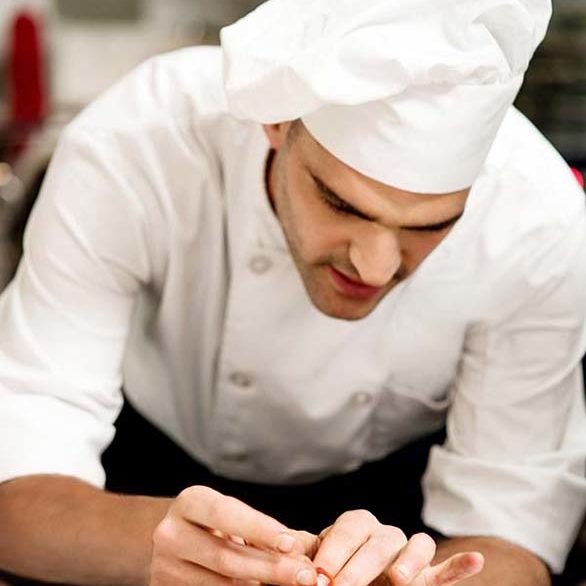 Male chef decorating salad of aubergine